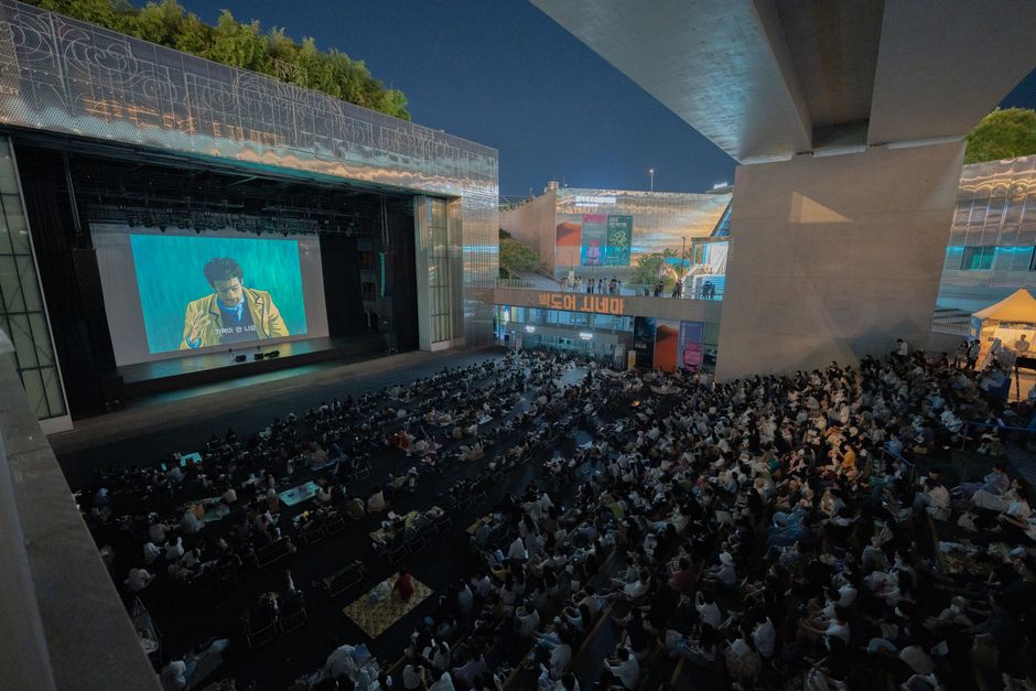공용 디지털 화면 앞에서 스마트폰을 사용하는 사람의 모습